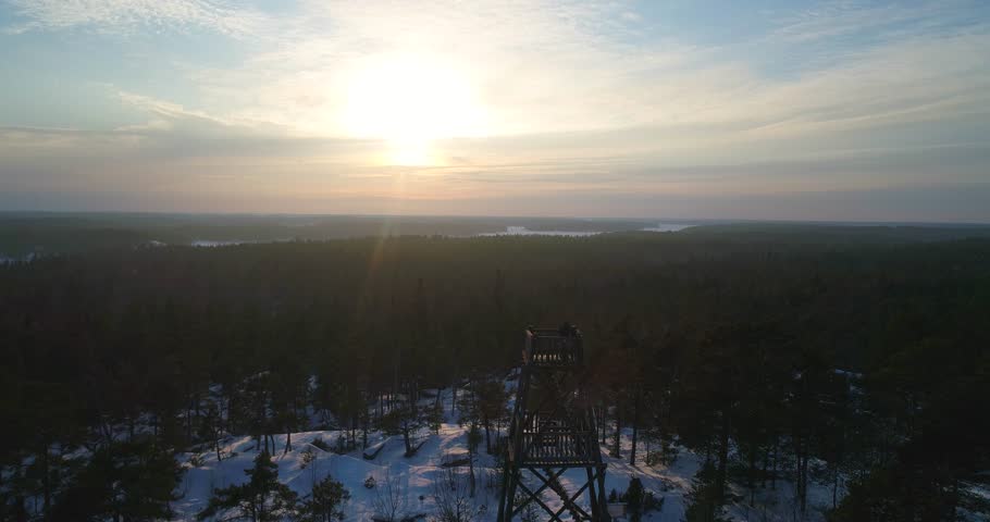 Observation tower, Cinema 4k view over a watchtower, revealing a snowy archipelago landscape, on a cold winter evening dusk, in Uusimaa, Finland
