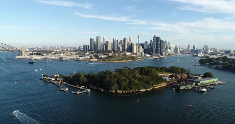 Goat island in front of Sydney city CBD Barangaroo and Darling harbour in aerial panning towards Sydney Harbour Bridge on a sunny summer day.
