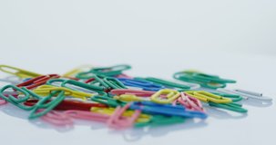 Macro shooting of the multicoloured paper clips falling down on the white background. Close up