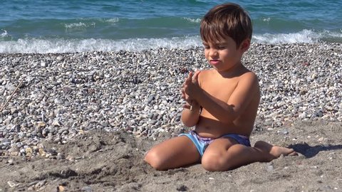 4K Zoom out kid sitting alone on the beach
