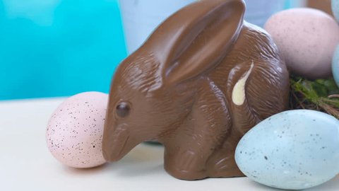 Australian milk chocolate Bilby Easter egg with eggs in nest against a blue and white background, dolly macro.
