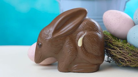 Australian milk chocolate Bilby Easter egg with eggs in nest against a blue and white background.