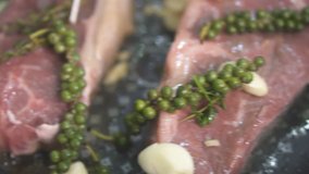 Closeup of delicious raw beef steaks placed on hot grill with fresh green pepper, fried butter and being heated in a pan - video in slow motion