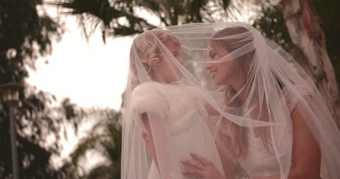 Young bride in wedding gown hugging cute little bridesmaid with flower basket on wedding day, videoclip de stoc