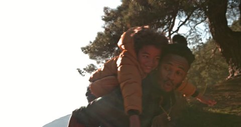Hipster father and son having fun with piggyback ride and running together in mountain forestの動画素材
