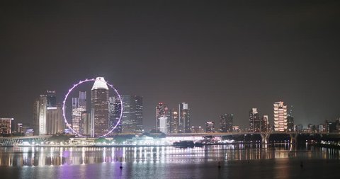 SINGAPORE, SINGAPORE - FEBRUARY 02, 2018: Singapore Flyer wheel and skyscrapers cityscape night reflections in water