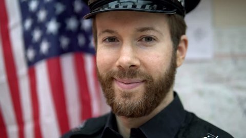 Portrait Of Brave American Cop, Happy Police Officer In Front Of US Flag 4K In Police Station.