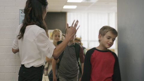 Enthusiastic teacher high-fiving students exiting doorway from classroom / Provo, Utah, United States