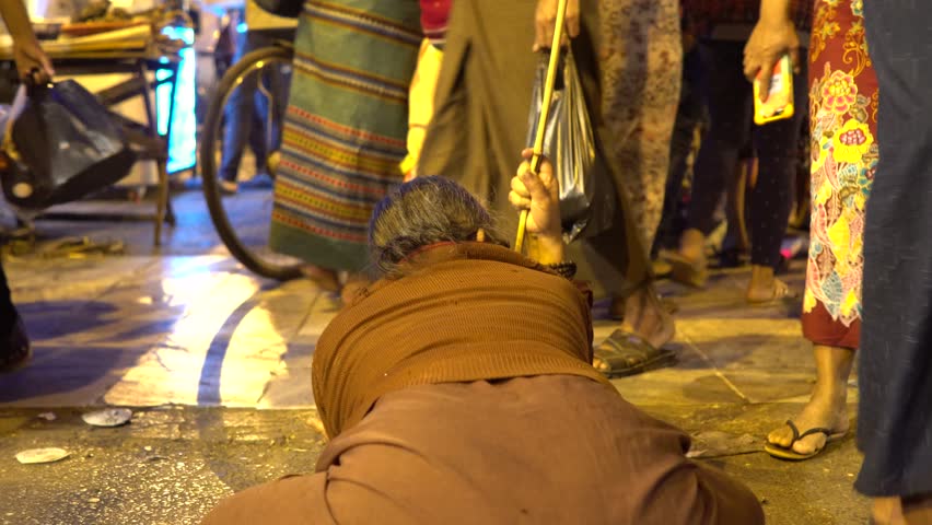 Beggar old woman near in market a Buddhist temple in Yangon, Myanmar. Poverty is a major issue in Myanmar