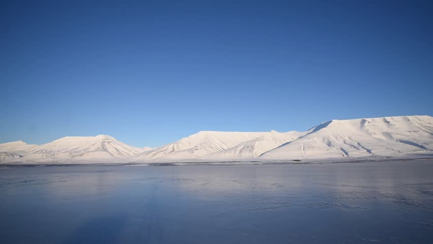 young loving couple playing on ice on a sunny day against the background of the snowy mountains of Spitsbergen Svalbard close to Longyearbyen city