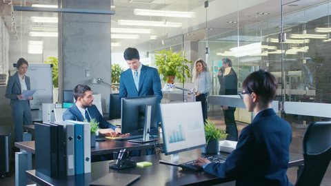Panoramic Shot of the Office where Associate Brings Important News to His Manager, Shows Him Tablet Computer with Information. Modern Glass and Concrete Building is Full of Busy Business People.