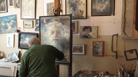 The old painter paints his own portrait with oil paint. 4K Video. 