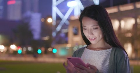 Woman sending sms on cellphone at night Stockvideo