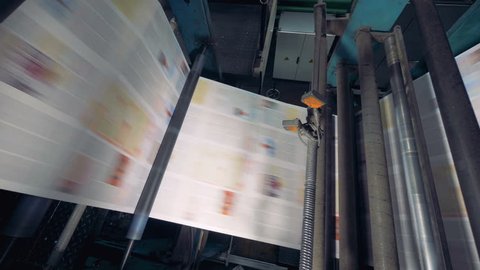 Newspaper printing by printing press at printing house.