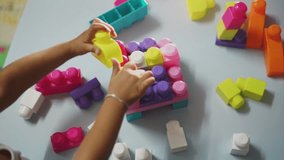 Little girl playing with colorful block.Real time footage of female asian kid playing with colorful mega block.Close up shot. 