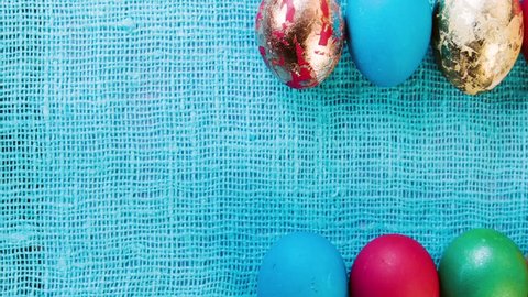 Multicolored beautiful Easter eggs are laid out in two horizontal rows on a cloth lilac, blue tablecloth. Celebratory background for easter. Space for text. Easter eggs closeup.