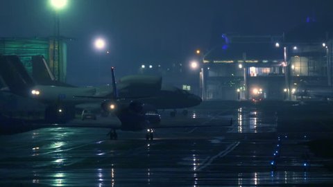 Business jet maneuvers the runway after landing at night. Back view 