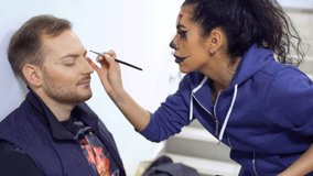 Actors prepares to perform on scene and makes greasepaint on face