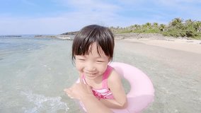 cute girl wearing lifebuoy and playing happily on the beach