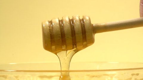 Scoop up honey with a wooden honey dipper from a glass container