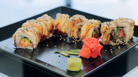 Sushi on a black plate decorated with roses in Ginger