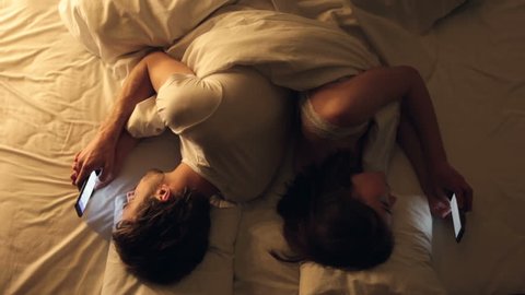 Couple crisis. Man and woman lies in the bed back to back and texting with their lovers.