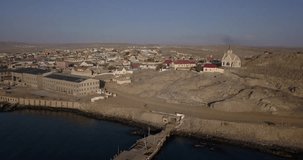 4K sunny afternoon aerial footage of brown granite rock boulders rocky mountains, Atlantic ocean horizons and views of small west coast historical harbour town Luderitz in southern Namibia, Africa