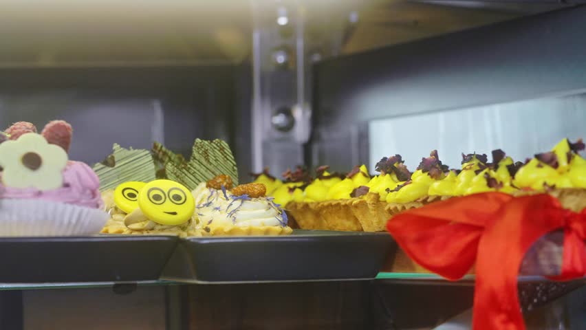 Fresh cakes on confectionery display. Camera movement - truck left.