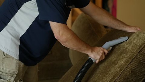 Professional cleans top of couch cushion with steam cleaner in this slow motion clip.