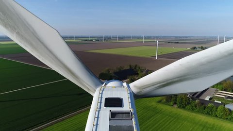 Aerial top down view wind turbine in polder landscape moving above the white modern construction of the wind turbine is device that converts winds kinetic energy into electrical energy 4k quality