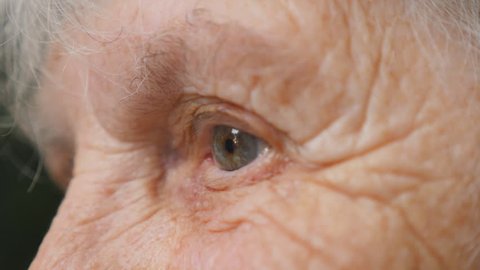 Close up portrait of old woman looking up. Eyes of an elderly lady with wrinkles around them. Side view Slow motion