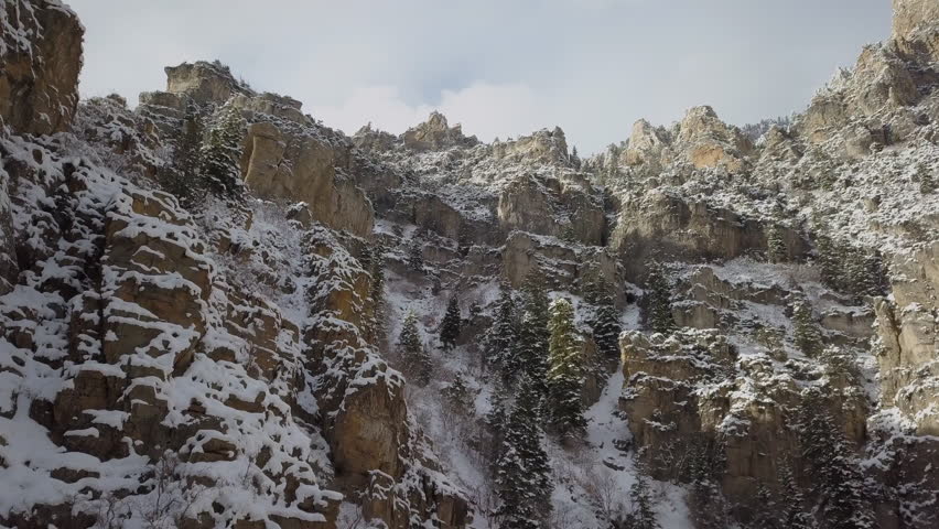 Flying up and over snow cover cliffs during winter in American Fork Canyon Utah.
