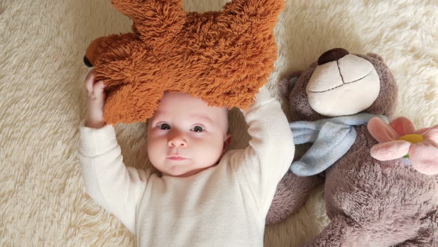 Little toddler is lying in bed with his teddy bear