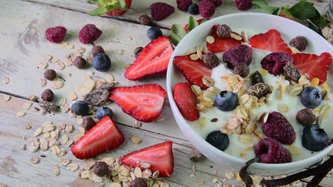 Healthy breakfast, cereal with yoghurt, strawberries, blueberries, raspberries and muesli on wooden rustic background. Concept of: fitness, diet, wellness and breakfast.