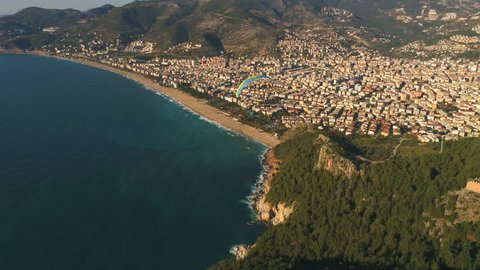 Aerial drone view of parashute jumper flying over beautiful Alanya, Mediterranean sea, famous Fortress on rocky hills of Taurus mountains in Antalya Province, Turkey.