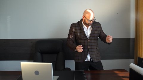 Businessman dancing excitedly at his desk in office. Young attractive Handsome business man funny dancing in office workplace. Happy young crazy businessman doing victory dance, successful achievement