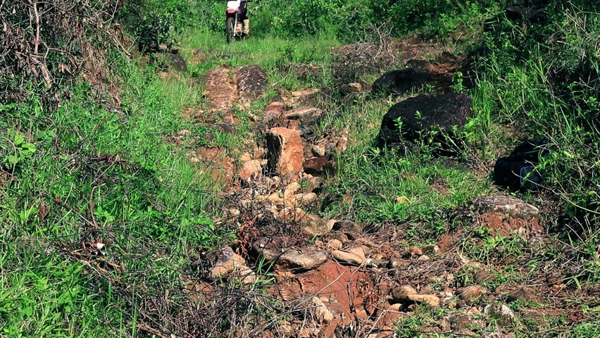 A trail full of big and scary rocks, witha rider going down fast on a dirt bike