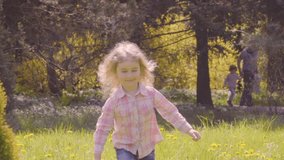 Cute little girl runs in park towards to the camera. Child is running around in the garden. Slow Motion.