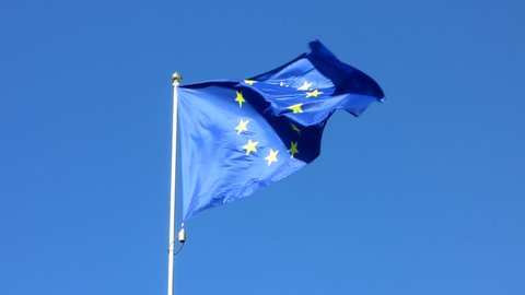 Flag of European union in the windy weather. Blue color background.