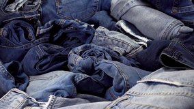 A pile of trendy blue jeans pants on a wooden background. HD video clip