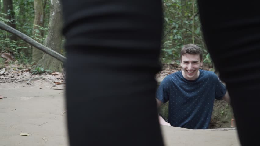Man standing in hole from Vietnam war. Laughing and explaining. Cu Chi Tunnels Vietnam.