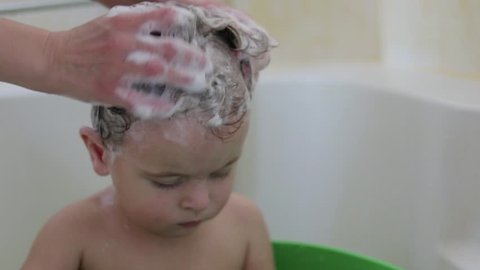Mommy is washing head her little daughter, slow motion video