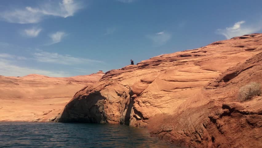 Lake Powell, Utah. A man jumps off of red rock cliff into the lake below. Lake Powell is a favorite destination for many activities, including cliff jumping.