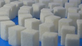 Sugar cubes pattern close-up on blue. Smooth rotation.