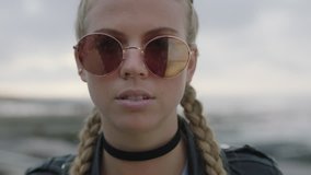 close up portrait of attractive blonde woman removes sunglasses looks confident to camera wearing leather jacket nose ring - Powered by Shutterstock - Get 15% off with code: PIKWIZARD15