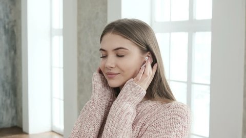 Portrait of young attractive girl listening to music on earphones. Pretty girl looking at camera and smiling.