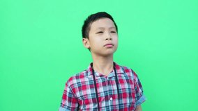 Young asian boy looking through binoculars in front of green screen