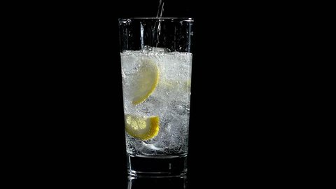 water with lemon and ice in a glass on a black isolated background
