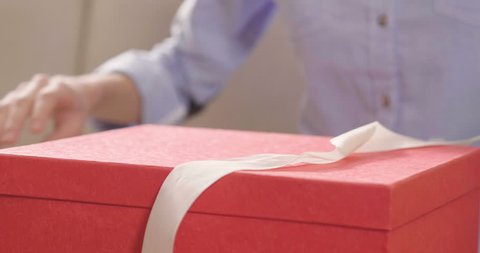 Close up of an young woman is opening a gift box arrived at home ordered by using online shopping. Concept of shopping, love, gift, anniversary.