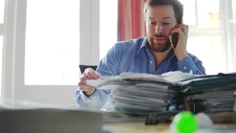 A Man In Debt Makes Phone Call, Concerned And Stressed With Bill Letters